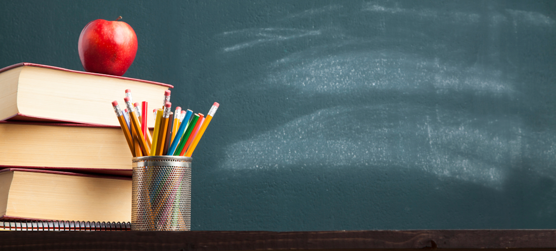 Chalkboard with pile of books, apple and pencils