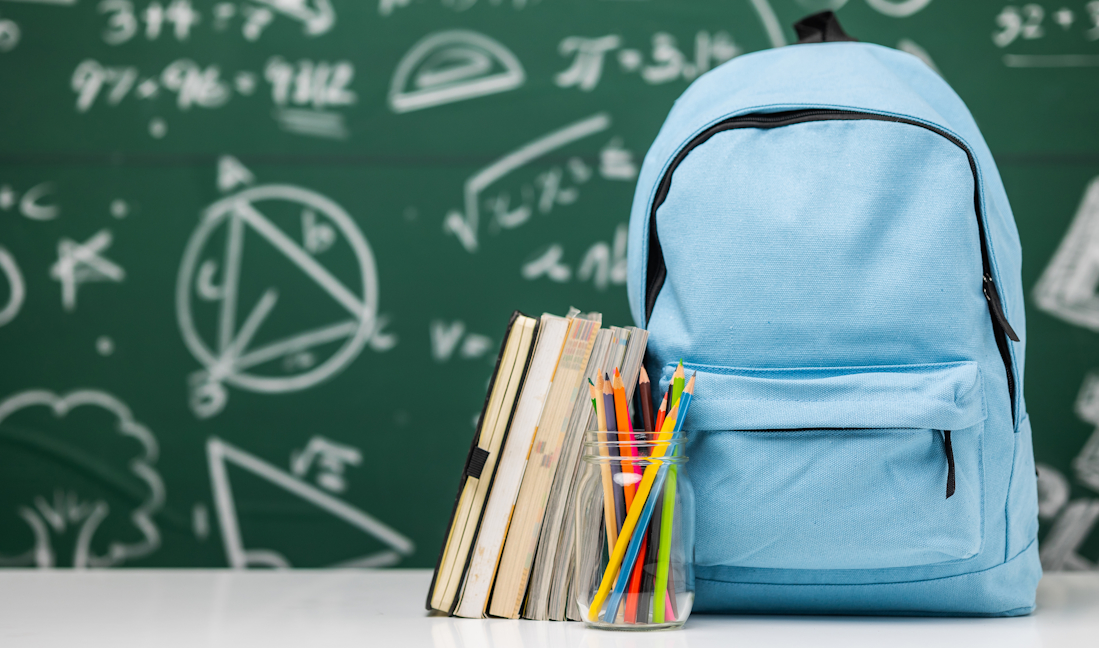 school bag and supplies in front of chalkboard